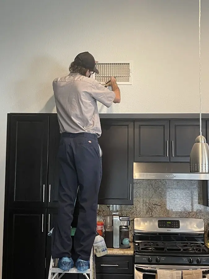 Technician inspecting an air vent during HVAC service in Deer Park